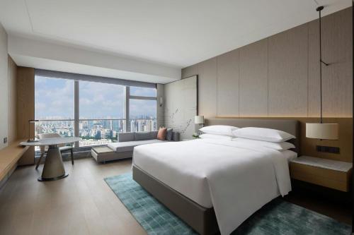 長沙市にあるChangsha Marriott Hotel Westの大きな白いベッドとリビングルームのある寝室