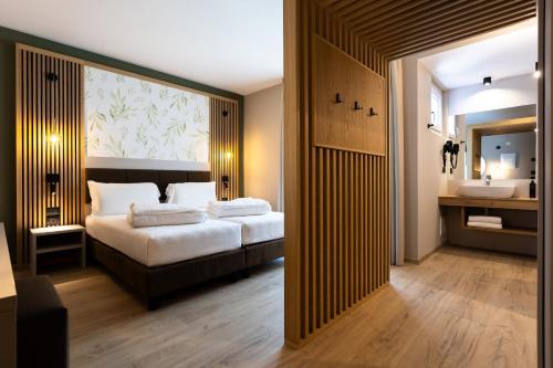a bedroom with a bed and a bathroom with a sink at Brione Green Resort in Riva del Garda
