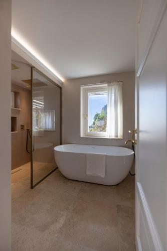 a large white bath tub in a bathroom with a window at Dimora de Feo in Amalfi