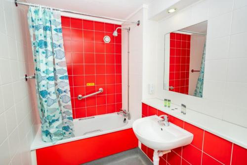 Baño rojo con lavabo y espejo en Bright Convenient Central Coventry Budget Studio, en Coventry