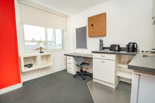 Una cocina con un escritorio y una silla en una habitación. en Bright Convenient Central Coventry Budget Studio, en Coventry