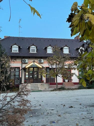 a building with a tree in front of it at Fenyves fogadó in Ásotthalom