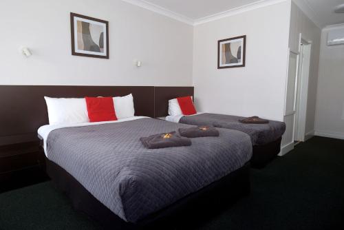 two beds in a hotel room with towels on them at Glynlea Motel in Horsham
