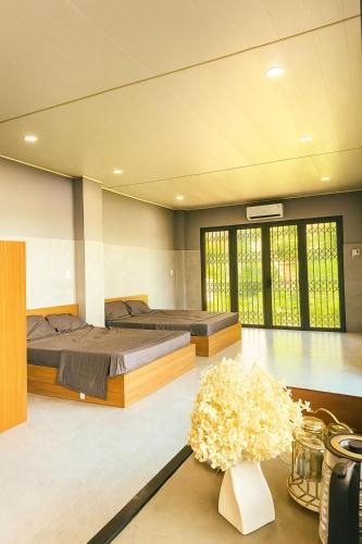 two beds in a room with flowers on a table at Happy House Sài Gòn in Ho Chi Minh City