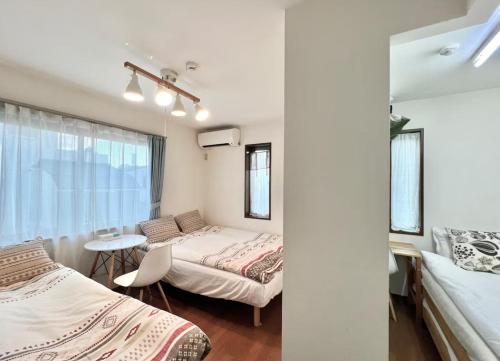 a bedroom with two beds and a table and a window at 直达-池袋-2分钟 车站徒步6分钟 3bedrooms-IT0338 in Tokyo