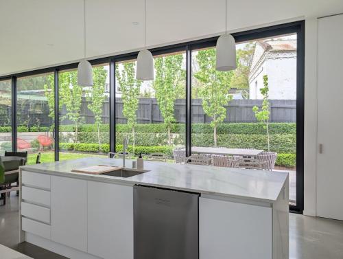 a kitchen with white cabinets and a large window at Donatella, Where Heritage Meets Haute Living in Bendigo