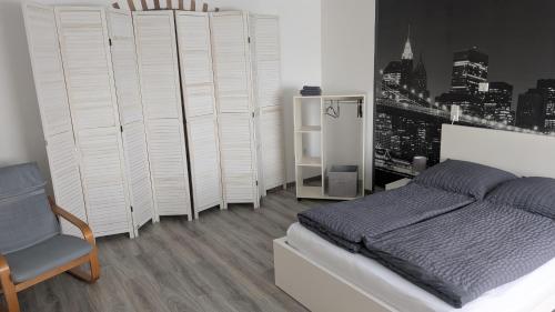 a white bedroom with a bed and a chair at " FeWo am Hof " Große Wohnung mit zwei Schlafzimmern, seperate Küche und großem Bad in Beverstedt