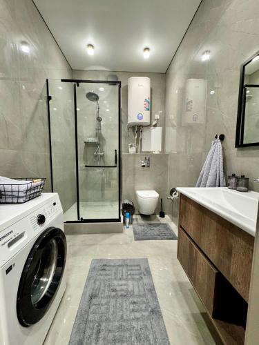 a bathroom with a washing machine and a shower at A-Six Apartment ЖК Достар in Karagandy