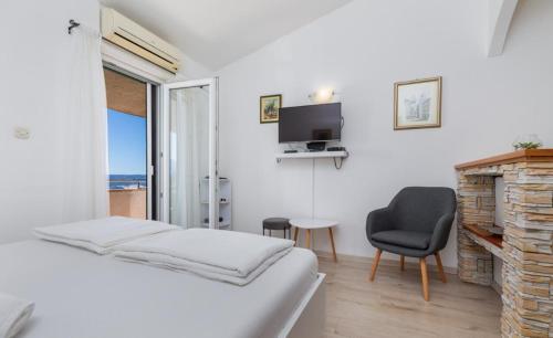 a white room with a bed and a chair and a television at Villa Marevista in Lokva Rogoznica