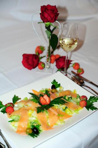 a plate of food on a table with a glass of wine at Hotel Restaurant Doppeladler in Rees