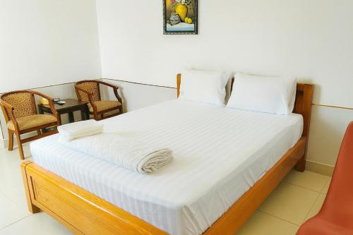 Khải Lộc Minh Hotel Hồ Chí Minh في مدينة هوشي منه: غرفة نوم بسرير ذو شراشف بيضاء و كرسيين