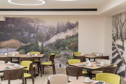 a restaurant with tables and chairs and a large painting at Trofonios Boutique Hotel in Levádeia