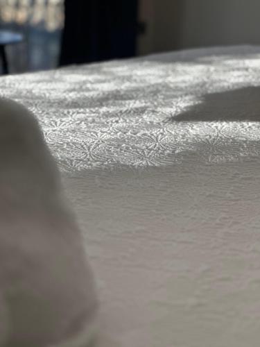 a close up of a bed with white sheets at Oxwich View Cottage in Swansea