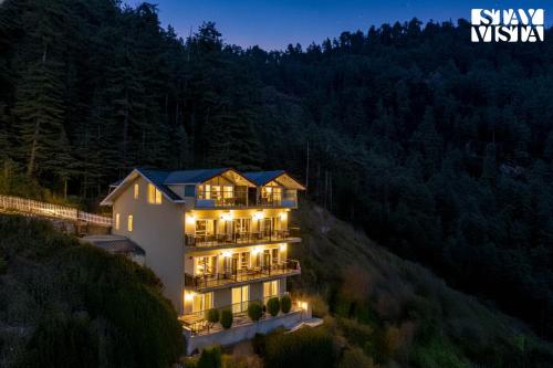 an aerial view of a building on a hill at night at StayVista at Ved Vilas in Kīar