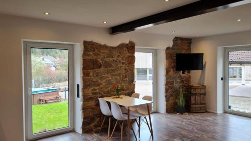 a dining room with a table and a stone wall at Modernes Apartment im grünen in Kleines Wiesental