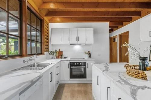 a white kitchen with a sink and a stove at Hahndorf Log Cabin in Hahndorf