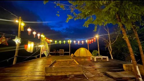 a deck with a tent and lights at night at บ้านไร่เสือโคร่ง in Ban Hua Nong