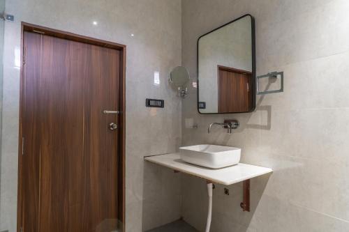 a bathroom with a sink and a mirror and a door at White House Royal Living in Jhānsi