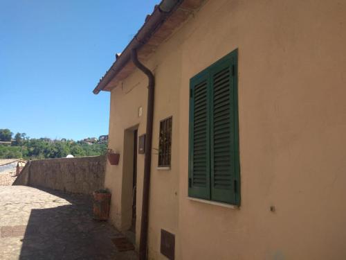 a building with a green window on the side of it at il nido di latera in Latera