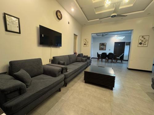 a living room with couches and a flat screen tv at Bridge Residency-2 Top City-1 Islamabad in Islamabad