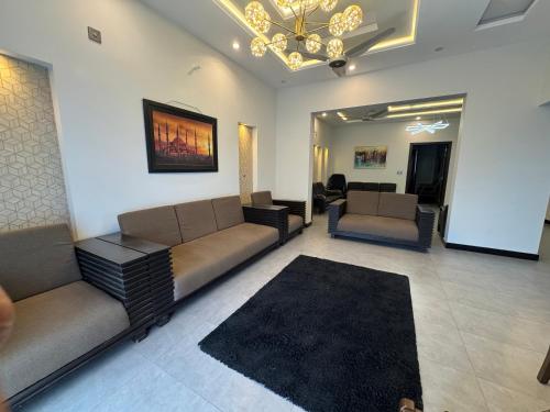 a living room with couches and a chandelier at Bridge Residency-2 Top City-1 Islamabad in Islamabad