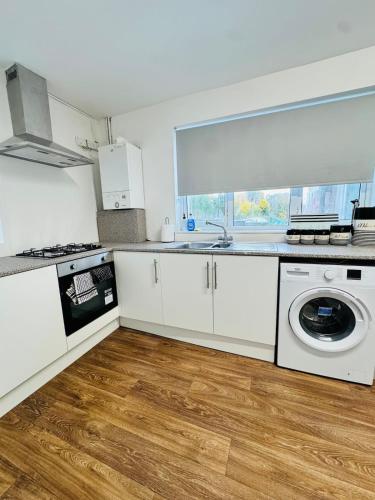 a kitchen with white cabinets and a washing machine at Swanky Dudley Retreat in Dudley