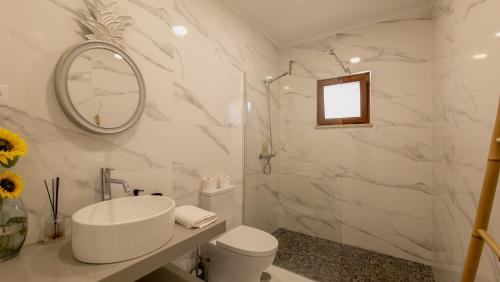ein weißes Badezimmer mit Waschbecken und Spiegel in der Unterkunft Casa Jasmim, Quinta Carmo - Alcobaça/Nazaré in Alcobaça