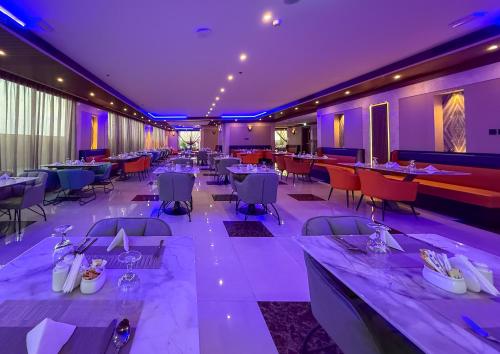 a restaurant with tables and chairs and purple lighting at Emora 1 BR Apartment in Dubai