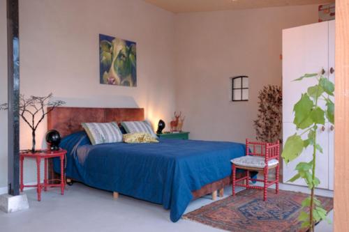 a bedroom with a blue bed and two red chairs at Logement de Appelgaard in Culemborg