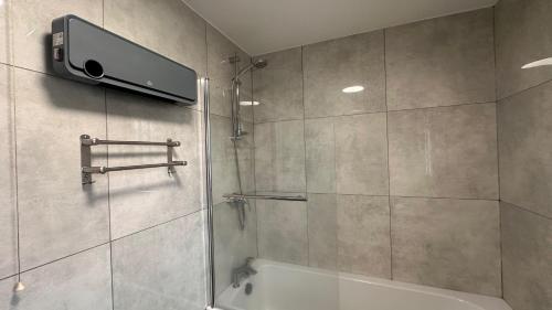 a bathroom with a shower with a tv on the wall at Apartment - Sleeps 4 - City Base - District Line in Dagenham Dock