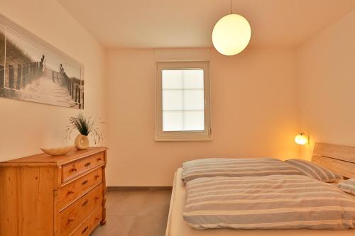a bedroom with a bed and a dresser and a window at Große Freiheit in Ostseebad Nienhagen