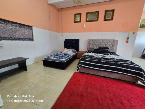 a bedroom with a bed and a couch and a red rug at Rumah Kak Ana in Pasir Puteh