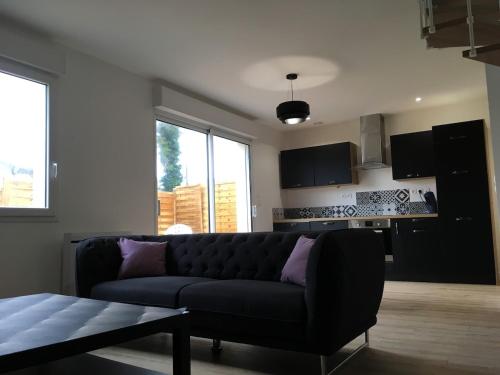 ein Wohnzimmer mit einer schwarzen Couch und einer Küche in der Unterkunft Maison de charme Saint Valery sur Somme Baie de Somme in Arrest