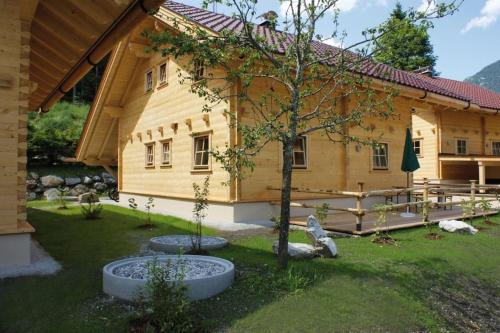 a large wooden house with a tree in the yard at Achenseer Hüttendörfl in Häusern
