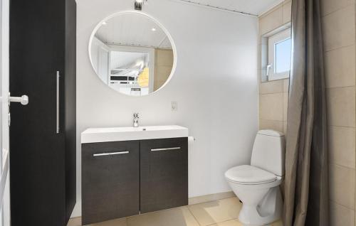 Un baño con lavabo, inodoro y espejo. en Cozy Home In Løgstør With Sauna, en Trend