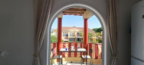 Un arco que conduce a un balcón con una mesa y sillas. en Weisshorn Bungalow 40, en Maspalomas