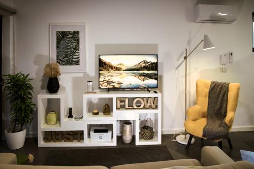 a living room with a tv and a yellow chair at InSide Furnas in Furnas