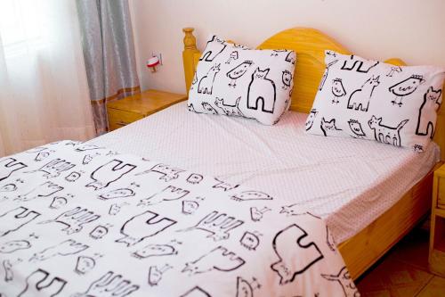 een bed met zwarte en witte lakens en kussens bij Cozy 3 bedroom house in Huye