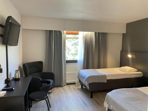a hotel room with two beds and a desk and a chair at Hotelli Puustelli Nivala in Nivala