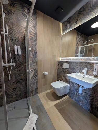 a bathroom with a shower and a toilet and a sink at Hotel Eden in Rzgów