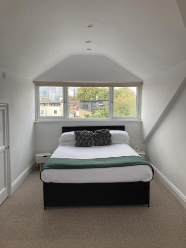 a bedroom with a bed with a large window at The Spacious Stay Stratford in London