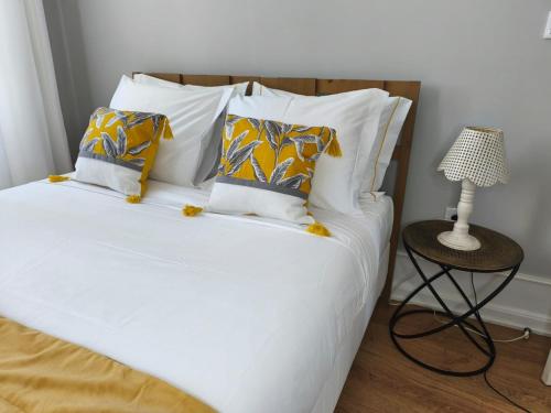 a bedroom with a bed with white sheets and a table at Mourisca 1810 Guest House in Águeda