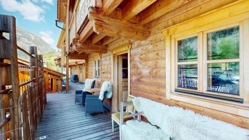 a porch of a log cabin with chairs and windows at Schlosswirt Chalet II in Großkirchheim