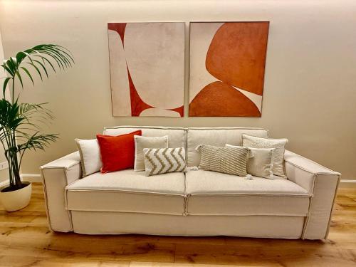 un sofá blanco en una sala de estar con pinturas en Cuneo Charme, en Cuneo