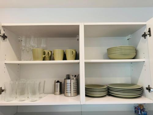 einem weißen Schrank mit Platten und Schalen in der Unterkunft Moderne, gepflegte helle Neubau-Einliegerwohnung in Rohrbach