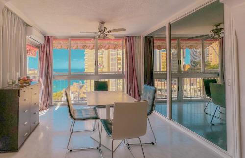 Un comedor con mesa y sillas y ventanas. en Carabelas 3, en Benidorm