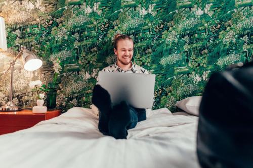 a man sitting on a bed using a laptop at Hotel Finn in Helsinki
