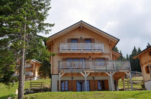 a log house with a balcony on top of it at Almliebe-Feriendorf Koralpe in Elsenbrunn