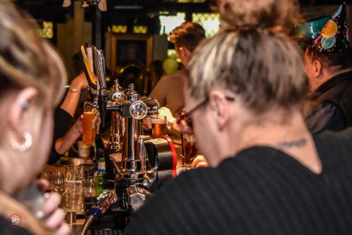 ミッチャムにあるCasuarina Treeの酒場に座ってビールを飲む人々