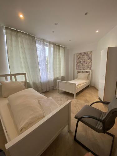 a white bedroom with a bed and a chair at Haven Hannover in Hannover
